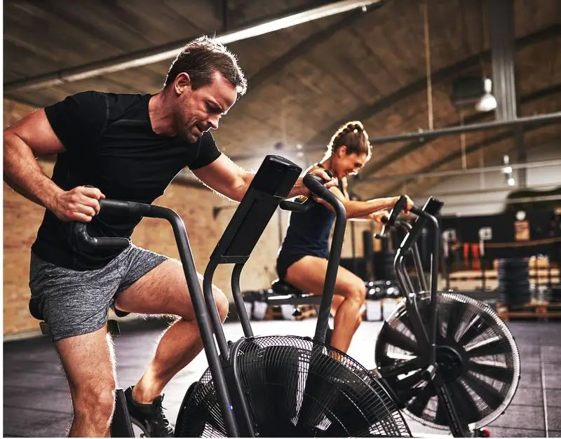 Trainer coaching a member during a class in a commercial gym